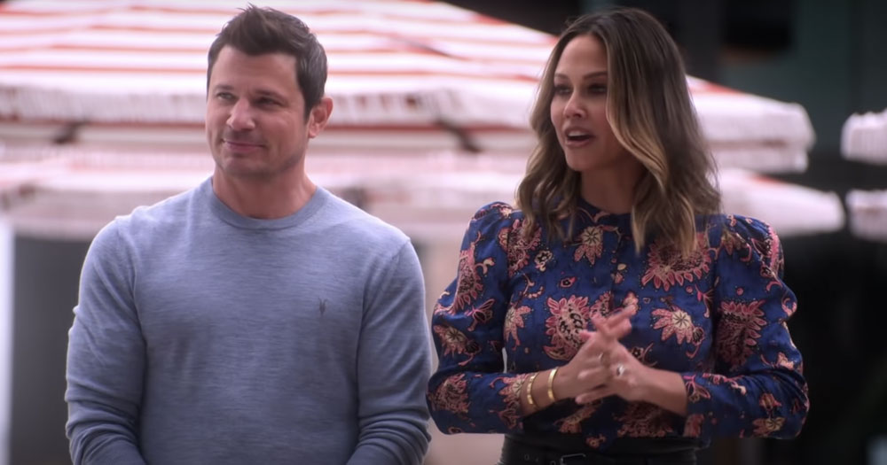 Still of Ultimatum hosts, Nick and Vanessa Lachey, in front of a summer parasol