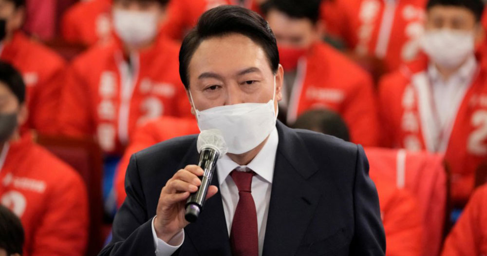South Korea President, Yoon Suk Yeol speaking to a microphone wearing a face mask.