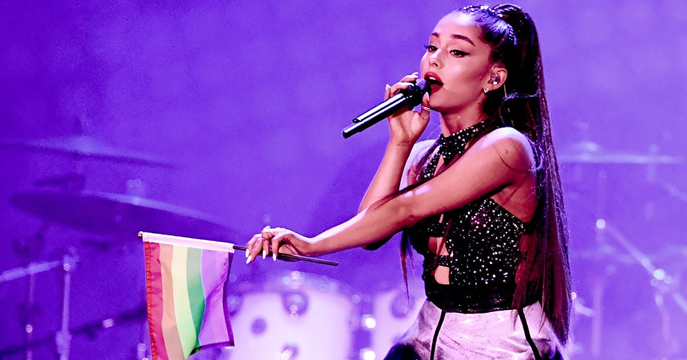 Ariana Grande performing with a rainbow flag as she sets up a fundraiser for Trans youth.