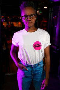 A model looking at the camera wearing a white T-shirt from the new GCN merch with a small circle that reads 'I'm pro pronouns'.