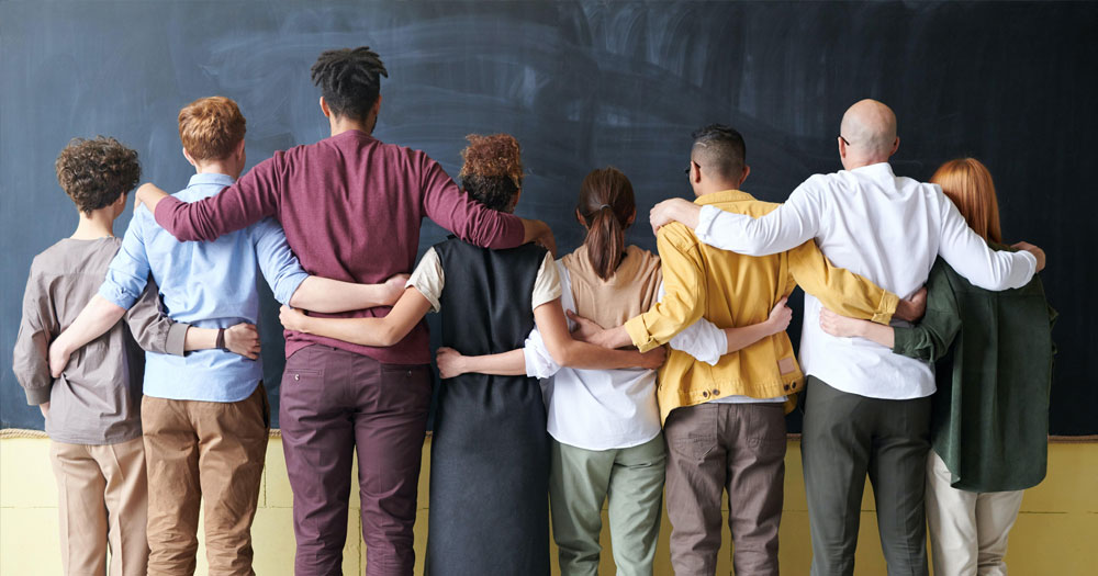 A group of people stand arm in arm as BeLonG To launches a new therapy service.