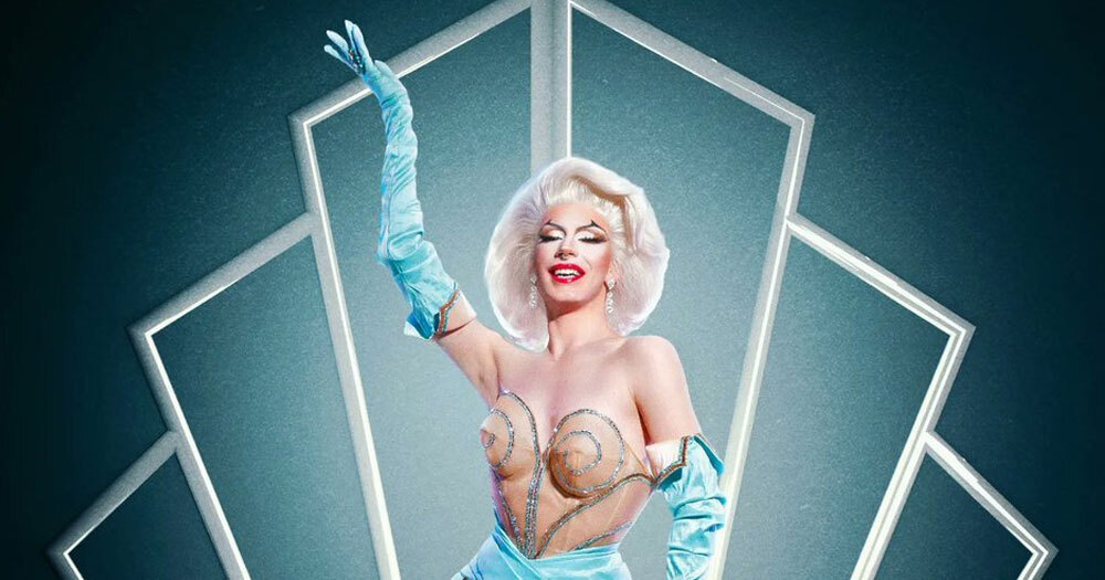 An image of Bosco wearing light blue gloves that run all the way up her arms. She is in a magnificent outfit and her hair looks like Marilyn Monroe's hair.