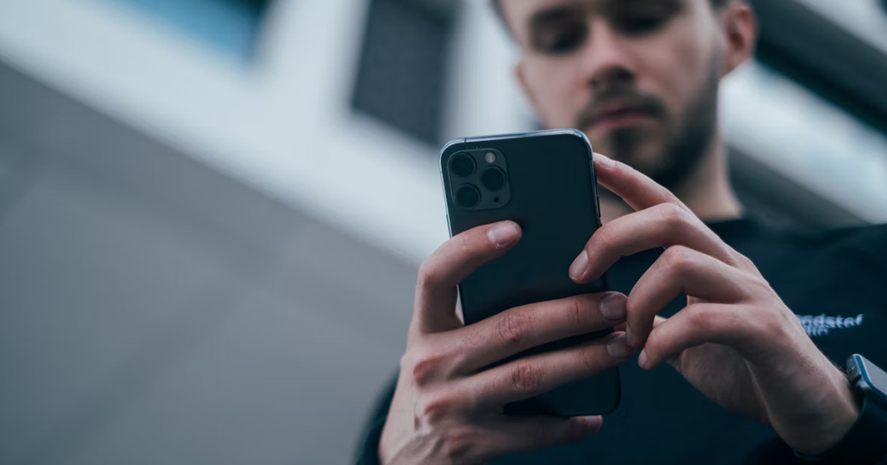 The hands of a me=an holding his phone. This article is about how to use dating apps safely.
