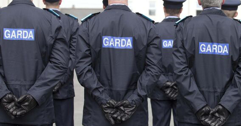 an image of seven men all wearing navy Garda jackets. Their jackets have GARDA written in large white text against a blue background.