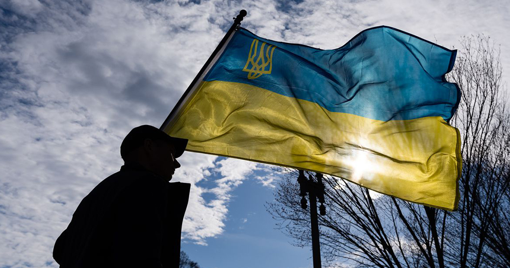 Silhouette of person flying Ukranian flag with coat of arms
