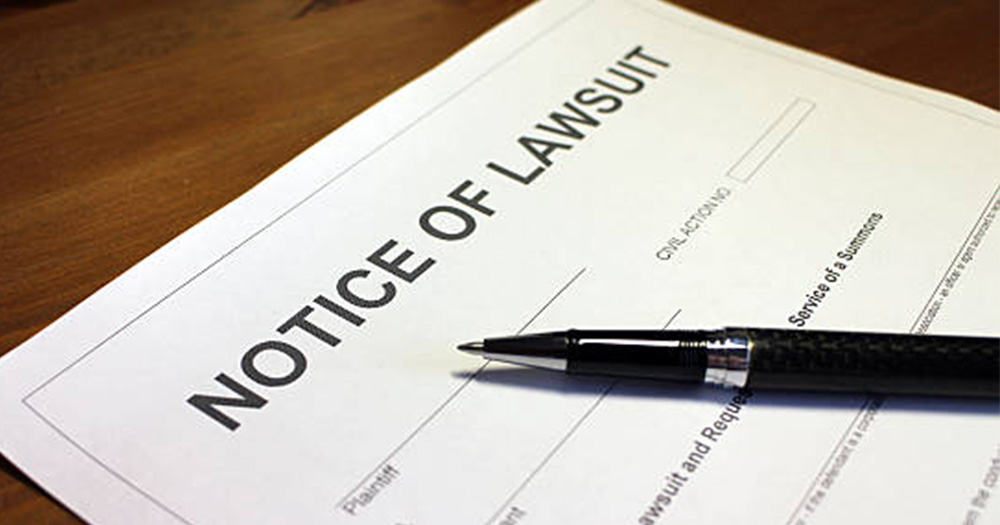 an image of a sheet of paper that has NOTICE OF LAWSUIT written in big black writing. There is also a pen resting on the sheet of paper.
