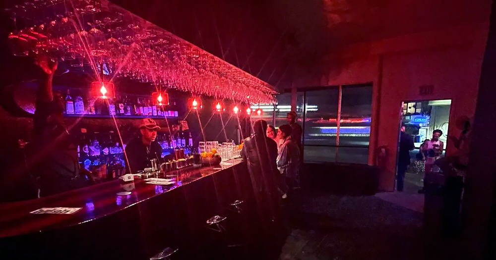 An image of the inside of the queer nightclub that was torched. There are two people sitting at the bar and the lights are pink.