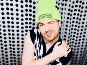 Photo of Apollo Monroe wearing a black and white checkered vest and a green hat.