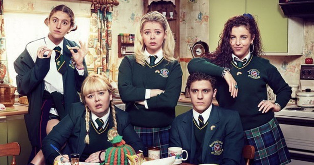 Cast of Derry Girls, that recently aired its finale, sitting and standing around a kitchem table wearing school uniforms