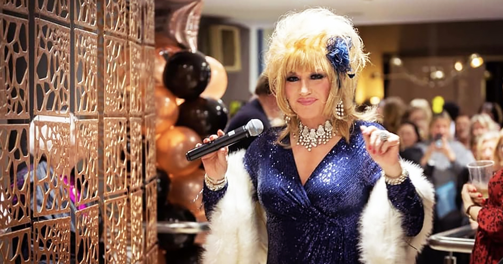 Mr Pussy, AKA Alan Amsby, standing on stage in drag with a microphone ready to perform