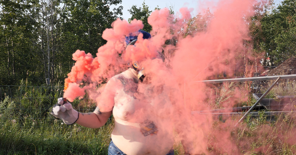 an image of a person with pink smoke in front of them. The smoke could possible be paint.