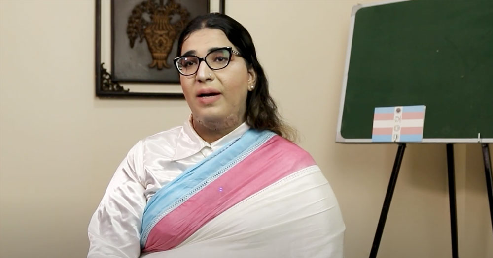 A woman is interviewed wearing a sari the colours of the Trans flag