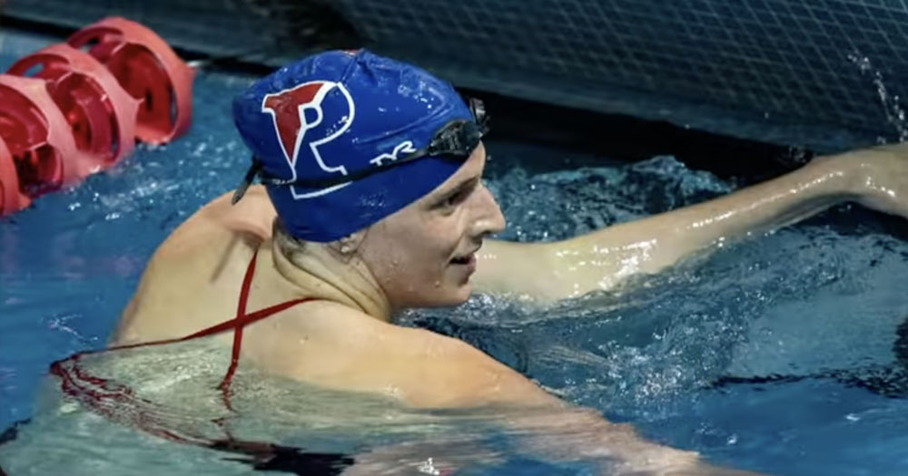 Transgender swimming athlete Lia Thomas in a pool wearing a swimming cap with goggles on her head