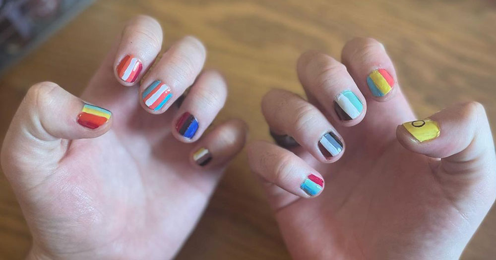 A pair of hands with all the nails painted in the style of different Pride flags