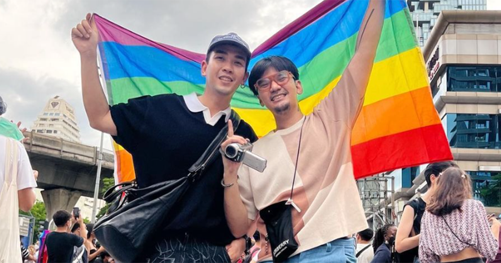 A same-sex couple in Thailand pose with rainbow flag.