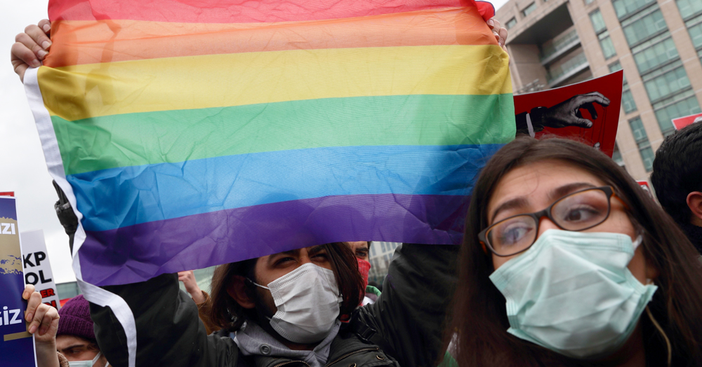 Two women in Turkey wearing Covid masks and holding up a Pride flag to fill the screen