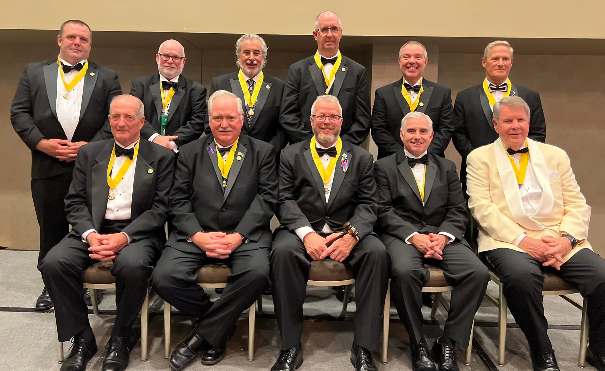 Large group of older men wearing yellow medals, posed for a congratulatory photo. Newly elected national board for Ancient Order of Hibernians.
