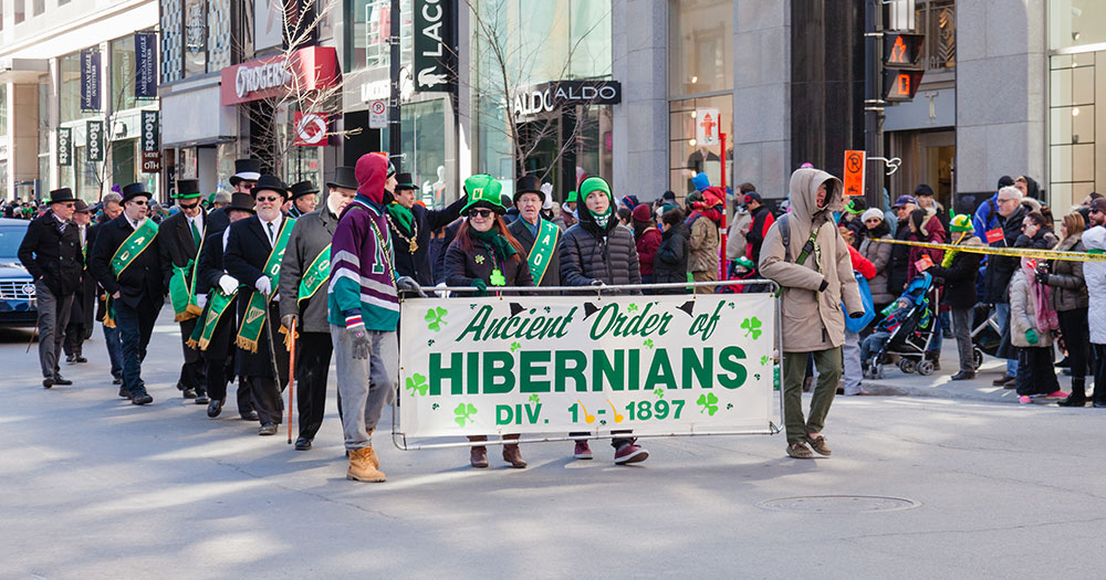 Group of people marching in a parade with a banner that reads: "Ancient Order of Hibernians"