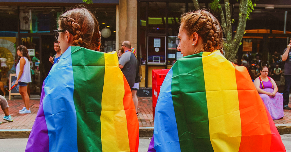 Young LGBTQ+ people are seen wearing rainbow flags. The BeLonG To survey is looking for young queer peopple to discuss their school experiences.