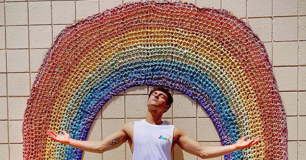 Olympic diver Tom Daley under a crocheted rainbow. A new documentary featuring Daley premieres soon on the BBC.