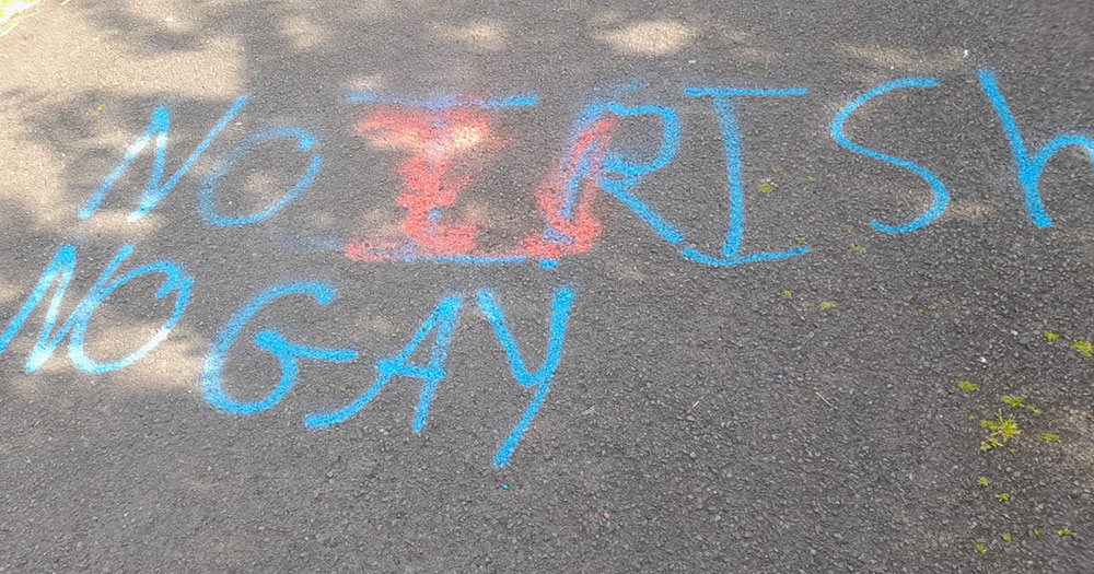 'No Irish No Gay' graffiti on a footpass in blue paint.