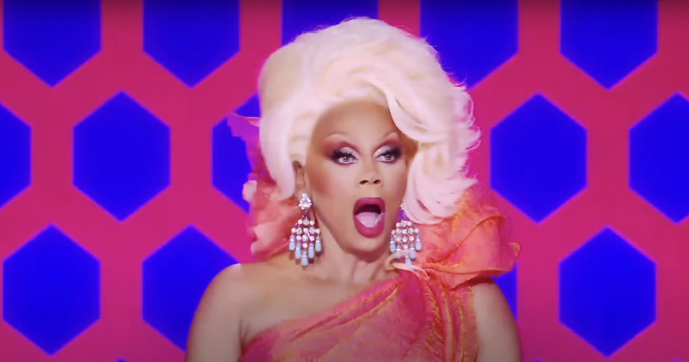 RuPaul in drag looking shocked as she judges queens on the main stage of Drag Race
