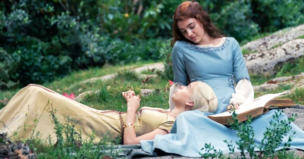 A frame from the TV show House of the Dragon, showing character Princess Rhaenyra lying on the grass with character Lady Alicent.