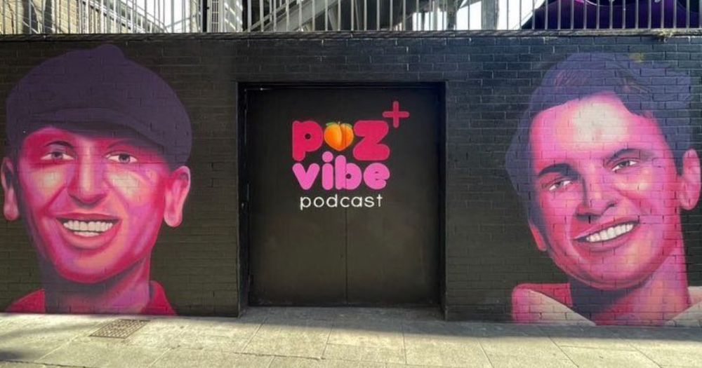 The photo of the mural on The George celebrating Poz Vibe has a white, pink and black painting of Robbie's face on the right and Veda's face on the left