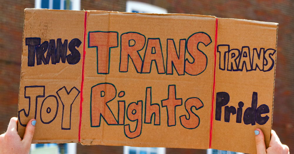 Small Trans Library Summer Series will be running from August 8 to August 15. Photo shows a sign reading 'Trans Joy. Trans Rights. Trans Pride'.