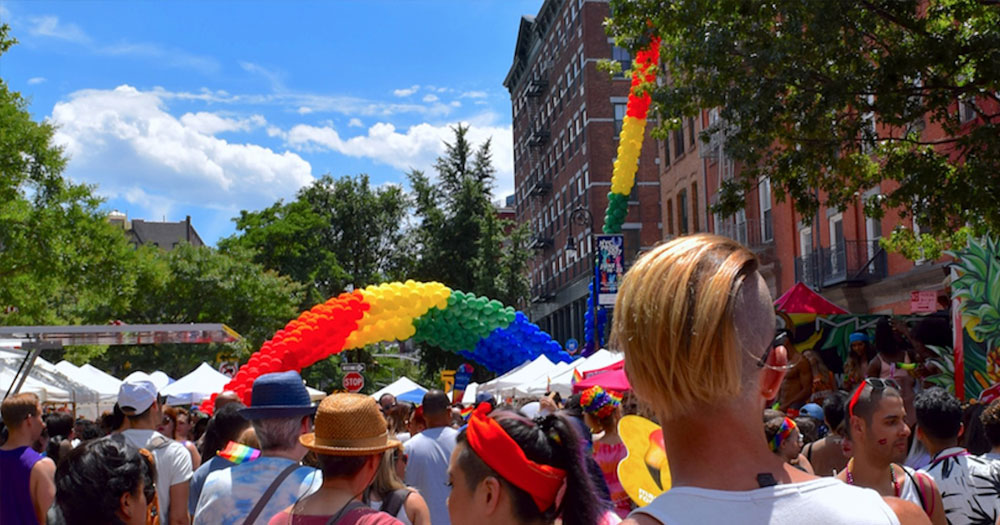 A Pride parade with rainbow balloons on a sunny day