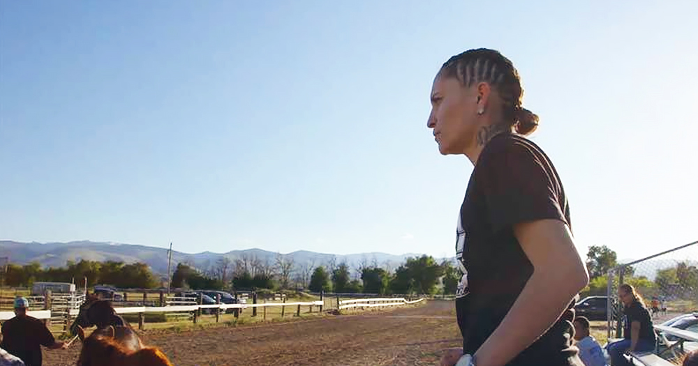 A Native American woman looking into the distance at a horse racing track