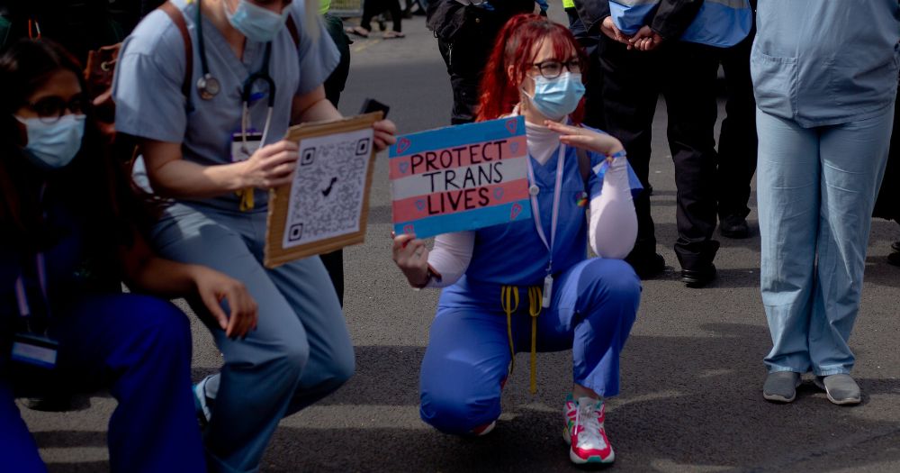 Photo of a nurse holding a "protect Trans lives" sign to illustrate Malta free gender-affirming surgery project