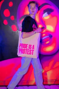 A model wearing a 'Pride is a protest' tote bag from the new GCN collection.