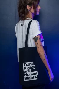 A model wearing a 'Trans Rights Are Human Rights' tote bag from the new GCN collection.