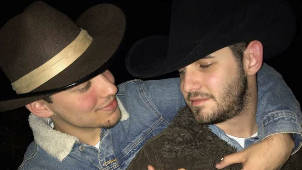Two men dressed as the main characters from the movie Brokeback Mountain. They are wearing cowboy hats and denim shirts