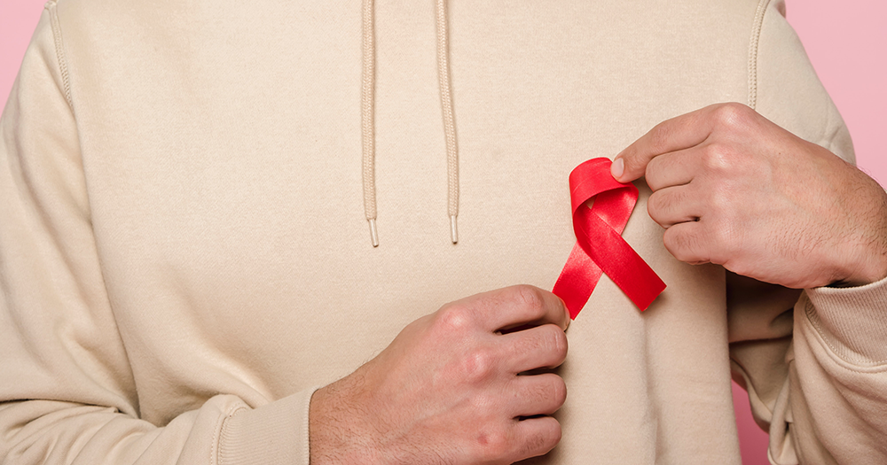 A person with a red HIV ribbon on their hoodie.