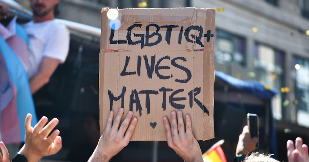 This article is about a bill on incitement of hatred. in the photo, two hands holding up a sign that reads 'LGBTIQ+ lives matter'.