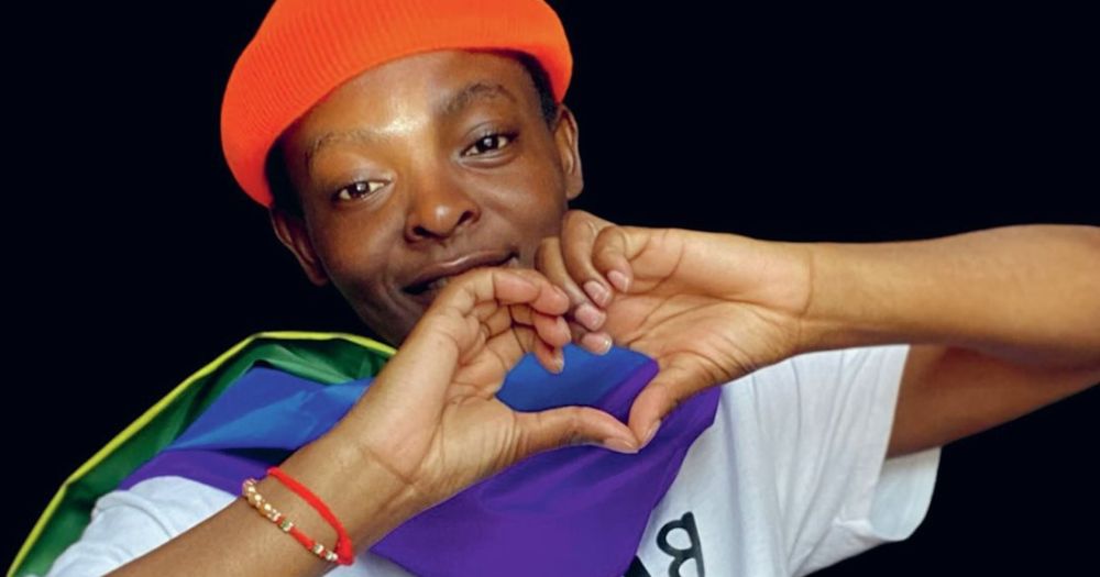 Beryl Ohas is seen making a heart shape with her hands while she wears a pride flag and talks about the struggles of gaining her refugee status in Ireland.