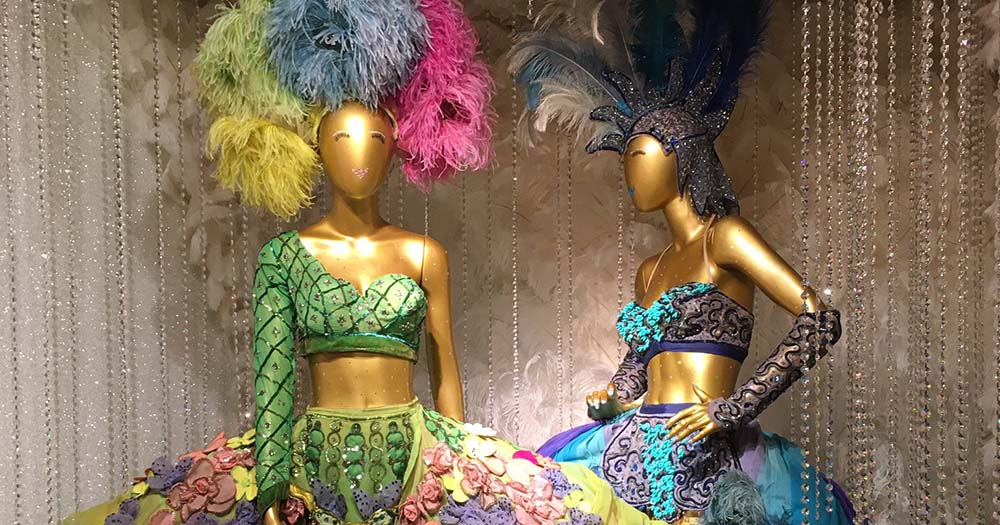 Two gold dolls wearing feather boas and dresses on display at the Museum of Broadway which is full of gay exhibits.