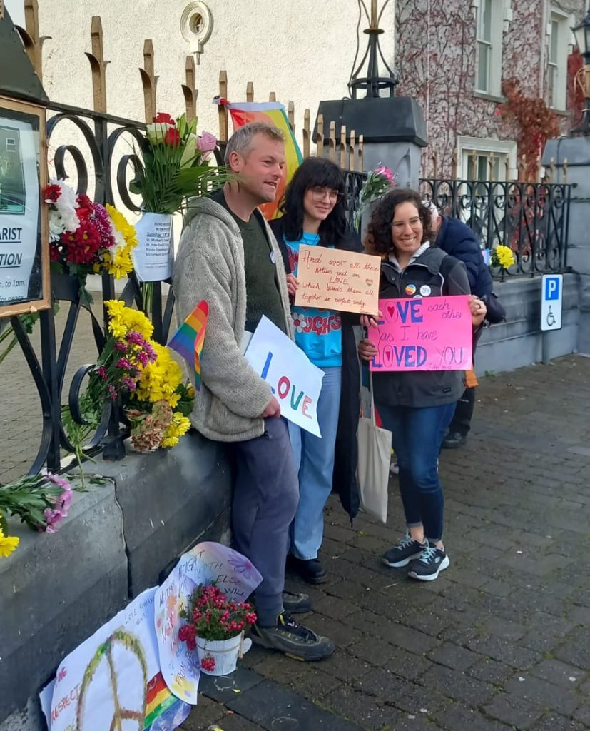 LGBTQ+ campaigners gathered in Listowel in front of St Mary’s Church, holding flowers and Pride flags.