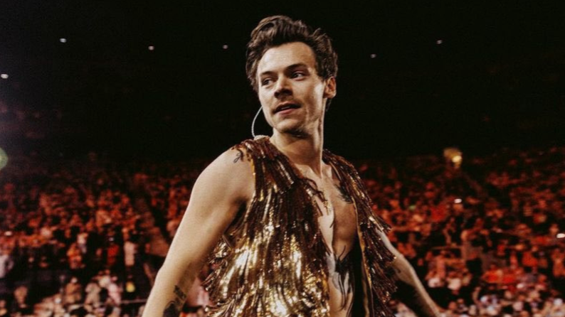 Harry Styles, an LGBTQ+ icon, is seen performing to a large crowd in the photo. He was announced to be nominated for several 2023 Grammy awards.