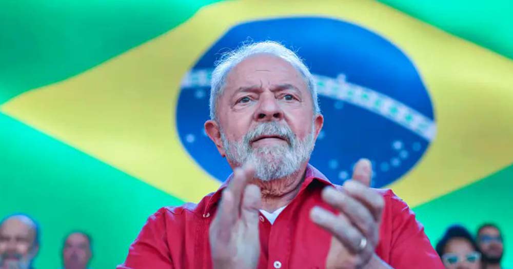 Lula clapping in front of a Brazilian flag celebrating his presidential victory in Brazil