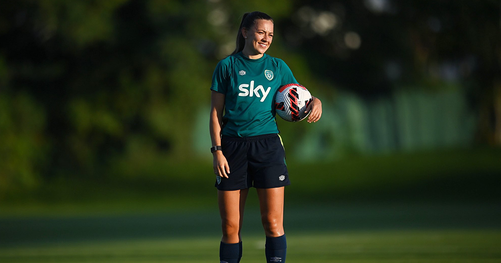 Katie McCabe smiling and holding a football.