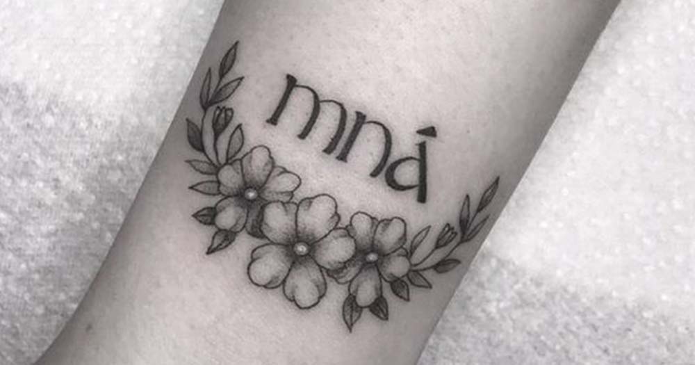 Black and white photo of a Project Mná tattoo with a fine line floral design.