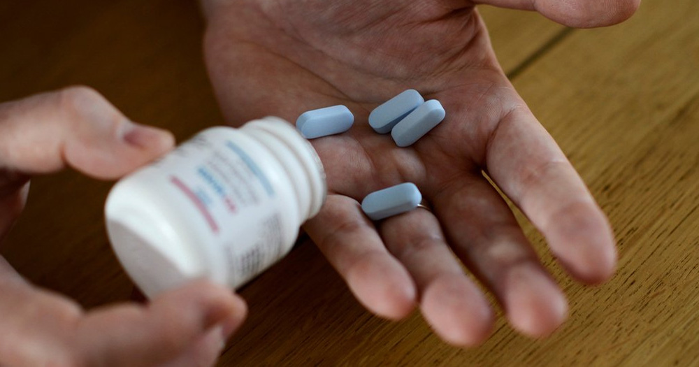A person is holding a bottle of blue medication, after they were able to access PrEP.