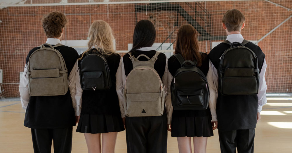 This article is about LGBTQ+ students feeling unsafe in schools. In the photo, students with their backs facing the camera in a school gym.
