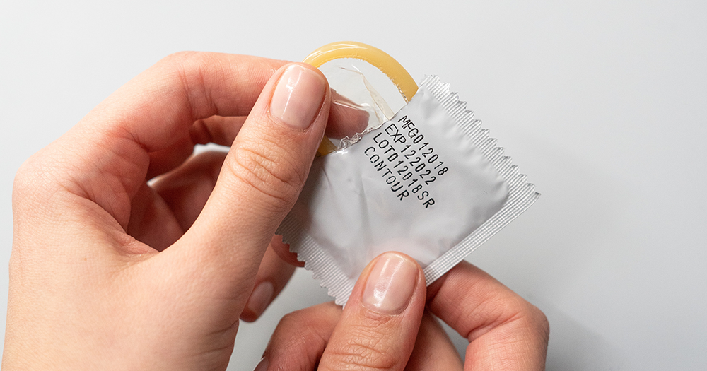 A person unwraps a condom (which is removed in the act of stealthing).