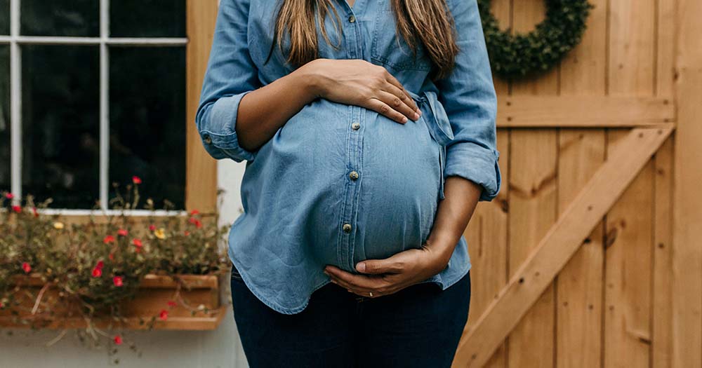 Pregnant woman in blue shirt represents new international surrogacy legislation in Ireland.