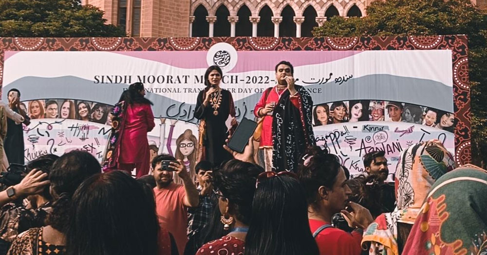 A march organised by the trans community in Pakistan, with activists speaking on a stage.