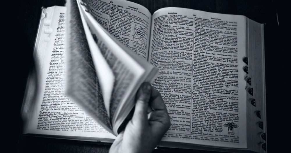 A person flips through the pages of Cambridge Dictionary where they have introduced a new description for the words 'man' and 'woman' including transgender men and women.